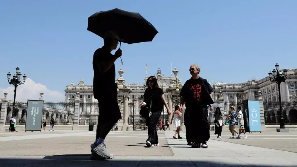 أحد المارة في مدريد يستخدم مظلة للاتقاء من أشعة الشمس خلال موجة حر في إسبانيا في الثاني من تموز/يوليو 2025 © توماس كوكس / ا ف ب